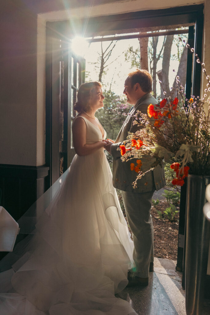 Bride and groom backlit by a golden sunburst in an open doorway