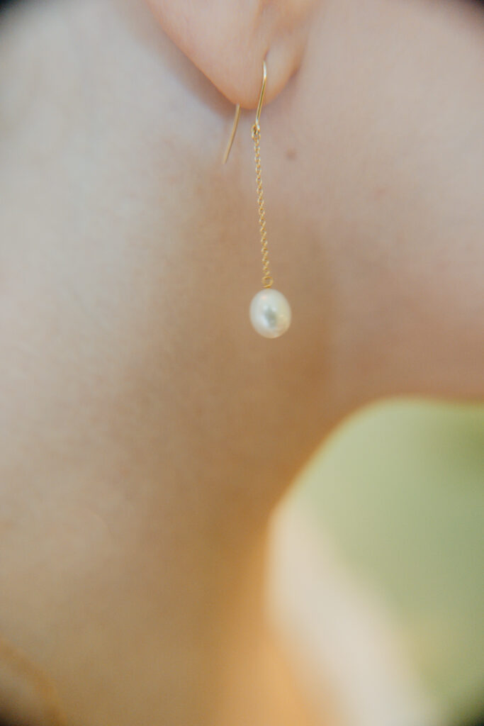 Close-up of a bride's pearl drop pendant necklace resting against her skin in soft natural light
