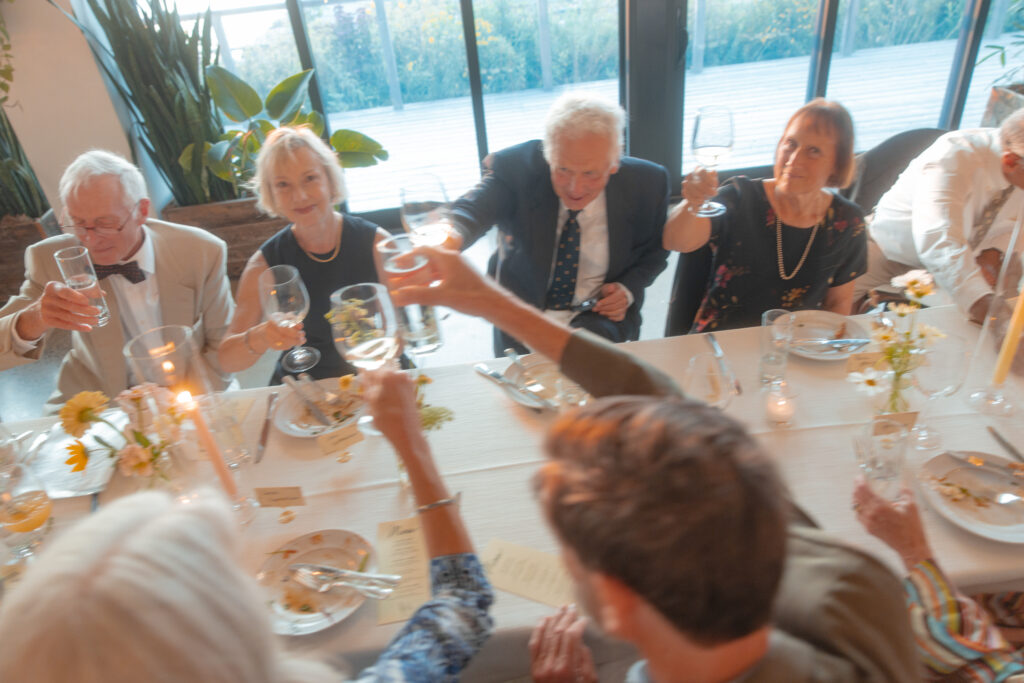 Wedding guests raising a toast around a long candlelit reception table