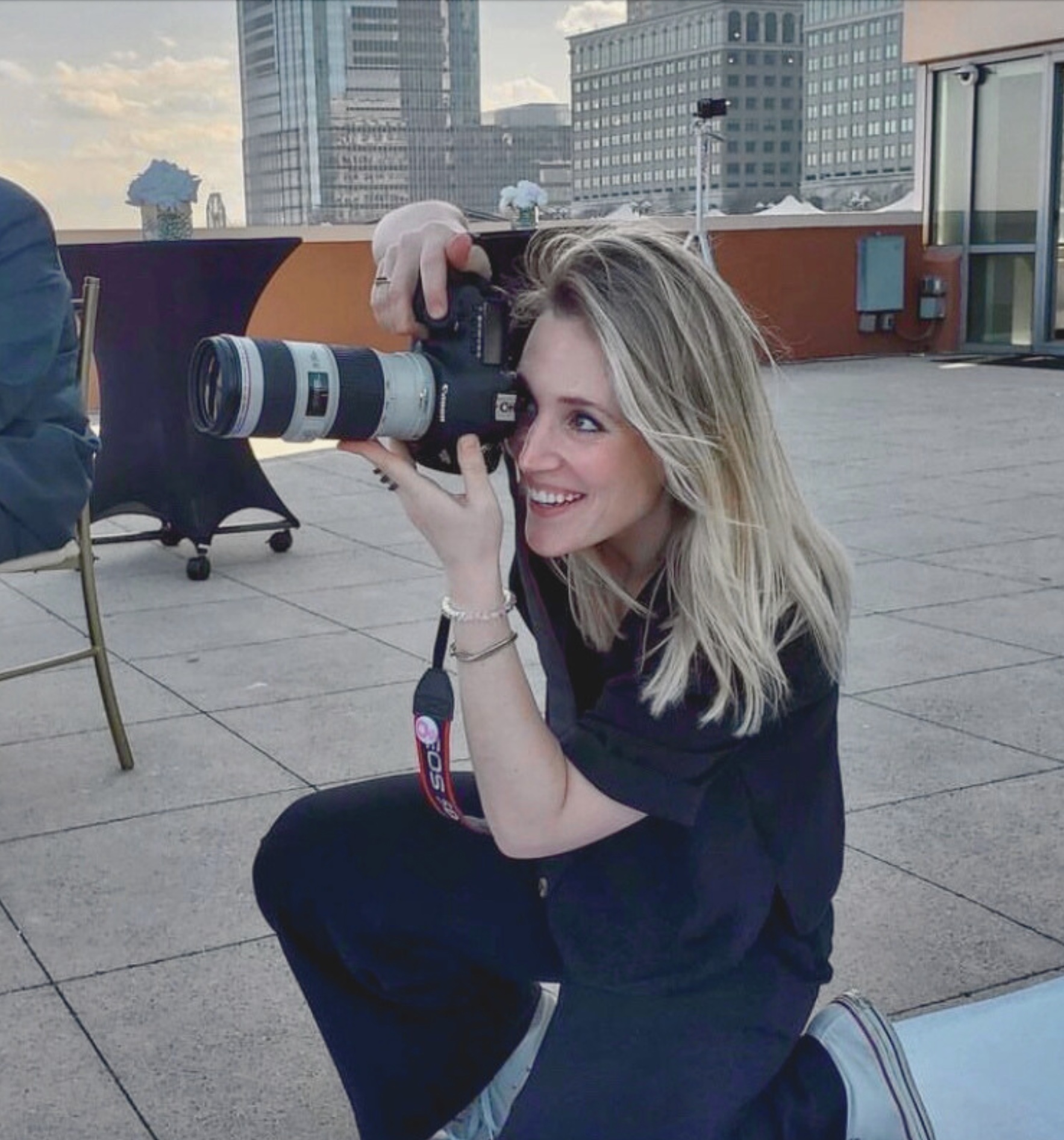 Lisa Bettencourt, Hudson Valley wedding photographer, shooting on a rooftop with the city skyline behind her
