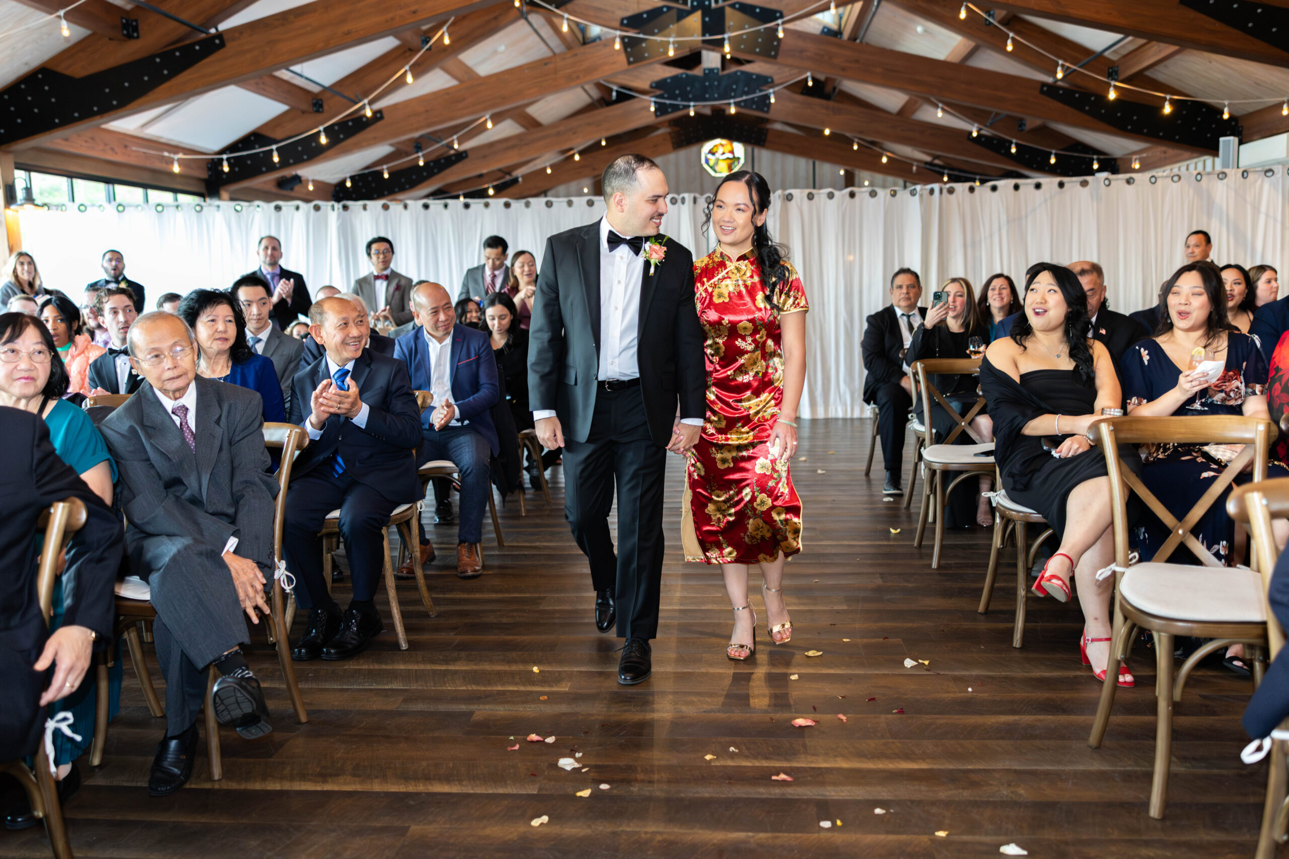Newlyweds walking back down the aisle as guests celebrate under a tented pavilion