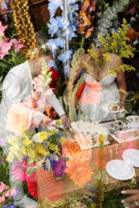 Newlyweds seated at a reception table surrounded by lush, colorful floral arrangements