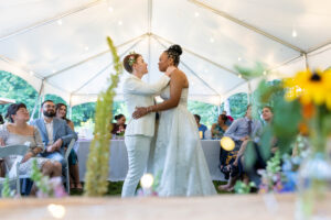 Couple sharing their first dance under a reception tent framed by sunflowers